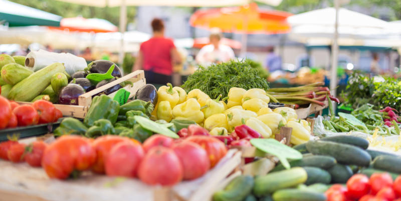 A selection of fruits and vegetables on a stand in an open-air food market