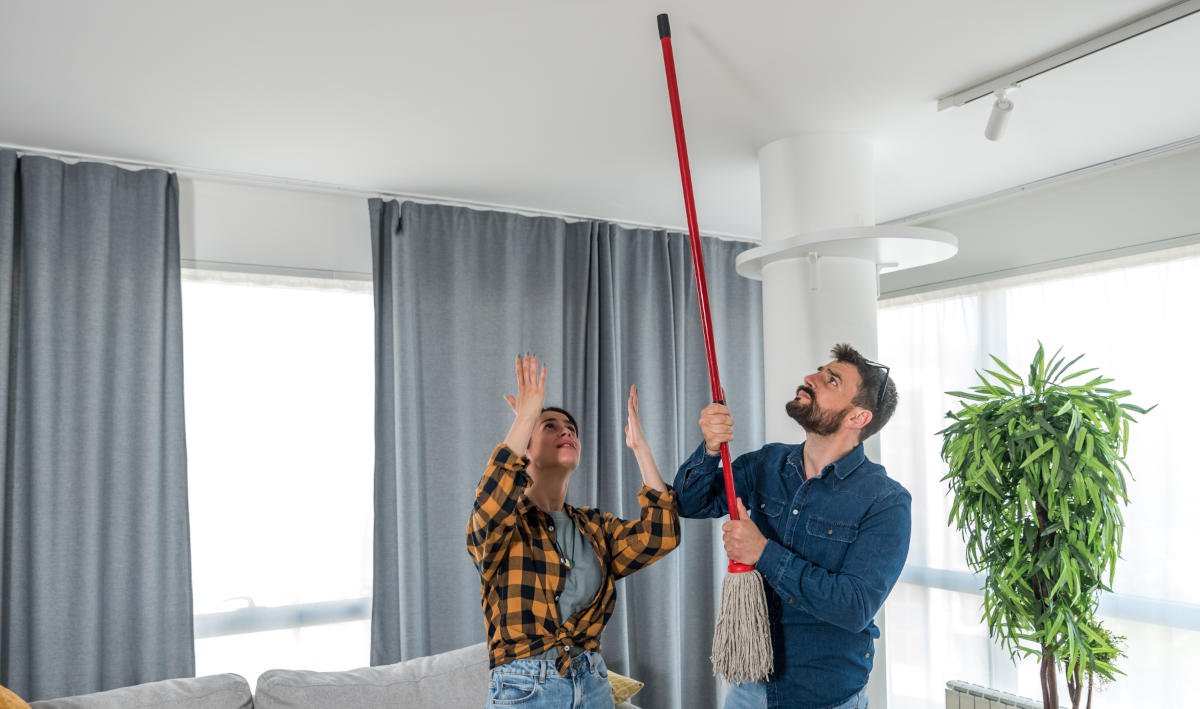 A young couple stares at the ceiling and yells because a neighbor upstairs is noisy