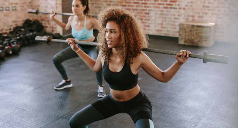 Two women lifting weights in a gym