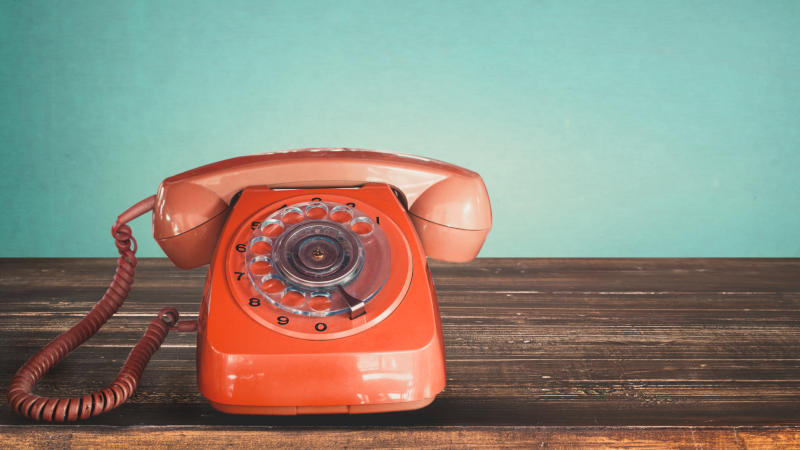 Old retro red telephone on a table with vintage green pastel background