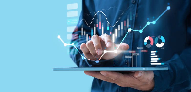 A man in a blue shirt tipping on a tablet. A chart is projected on top of the tablet.