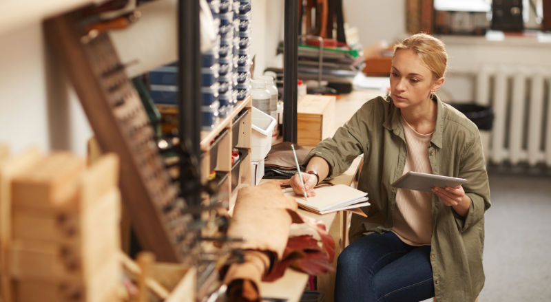 A serious looking woman sitting at a table in a wokrshop